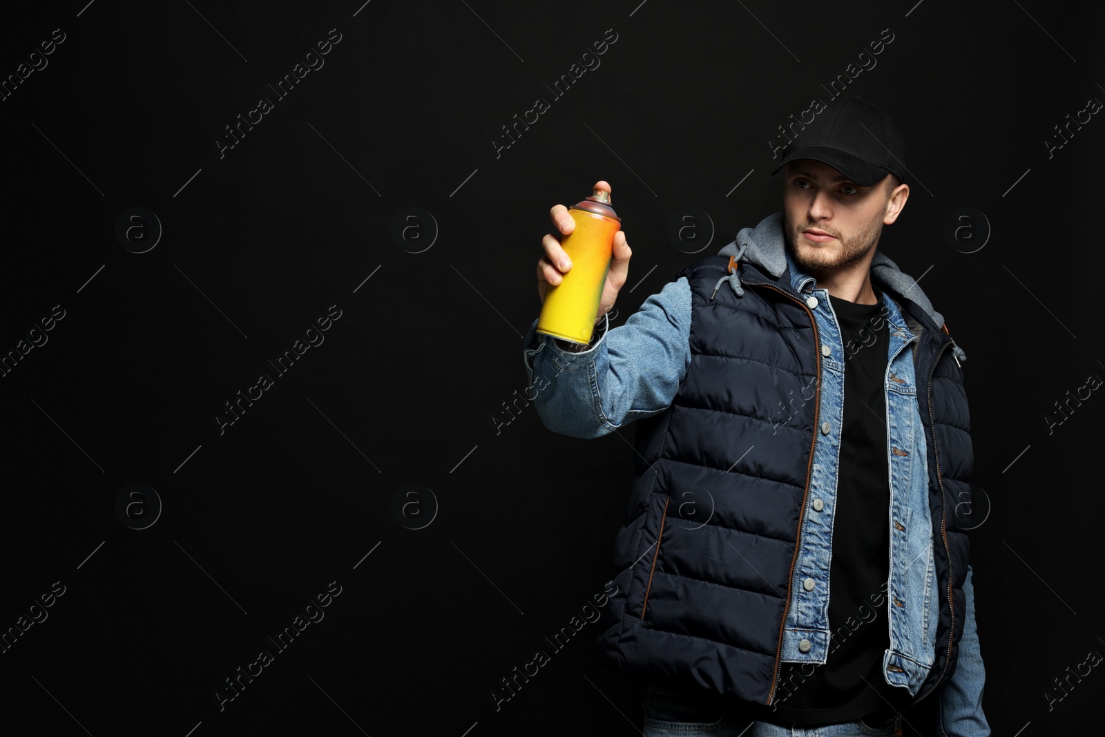 Photo of Handsome man holding used can of spray paint on black background. Space for text