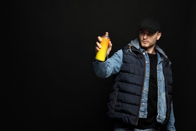 Photo of Handsome man holding used can of spray paint on black background. Space for text