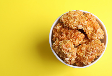 Photo of Bucket with yummy nuggets on yellow background, top view