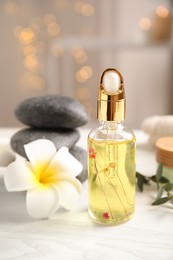Photo of Beautiful spa composition with essential oil and plumeria flower on white table against blurred lights