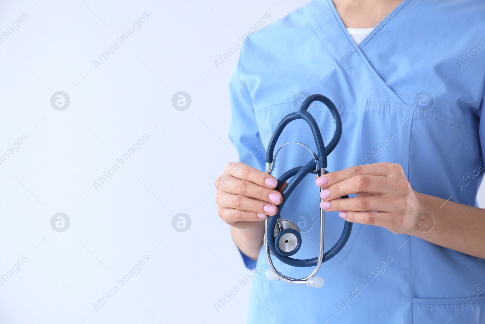 Photo of Closeup view of young doctor with stethoscope on light background