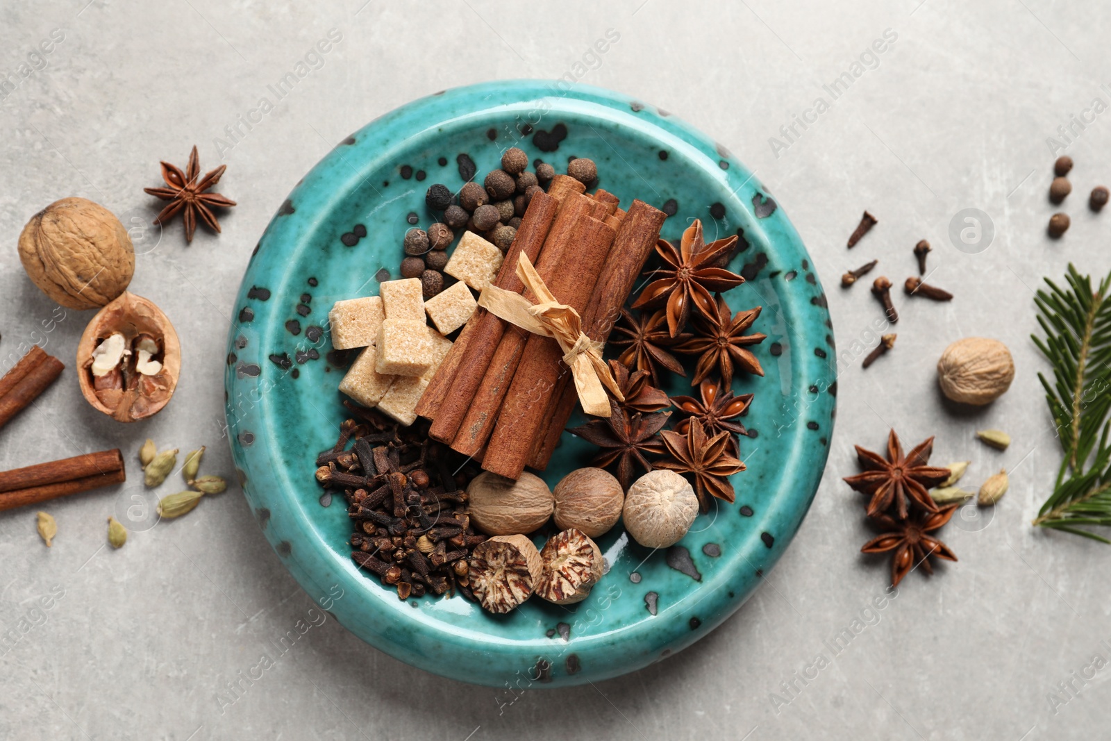 Photo of Different aromatic spices and fir branches on light textured table, flat lay