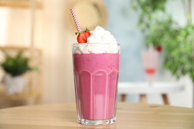 Photo of Tasty fresh milk shake with strawberry on wooden table indoors