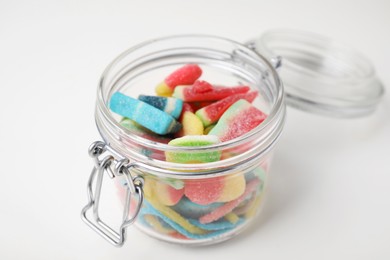 Tasty jelly candies in open jar on white table, closeup