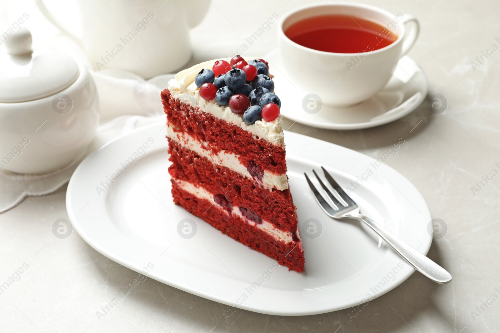 Photo of Plate with piece of delicious homemade red velvet cake on table