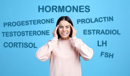 Image of Hormones imbalance. Stressed young woman and different words on light blue background