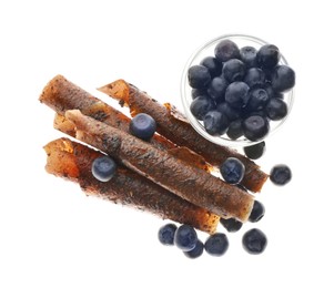 Photo of Delicious fruit leather rolls and blueberries on white background, top view