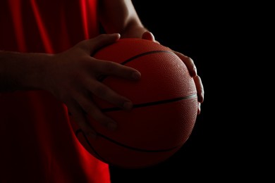 Photo of Basketball player with ball on black background, closeup