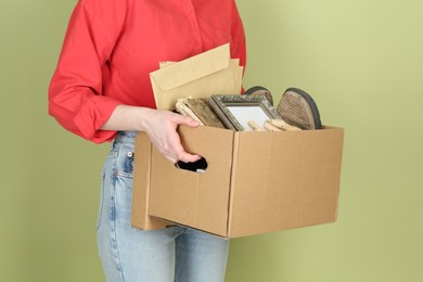Photo of Woman holding box of unwanted stuff on green background, closeup