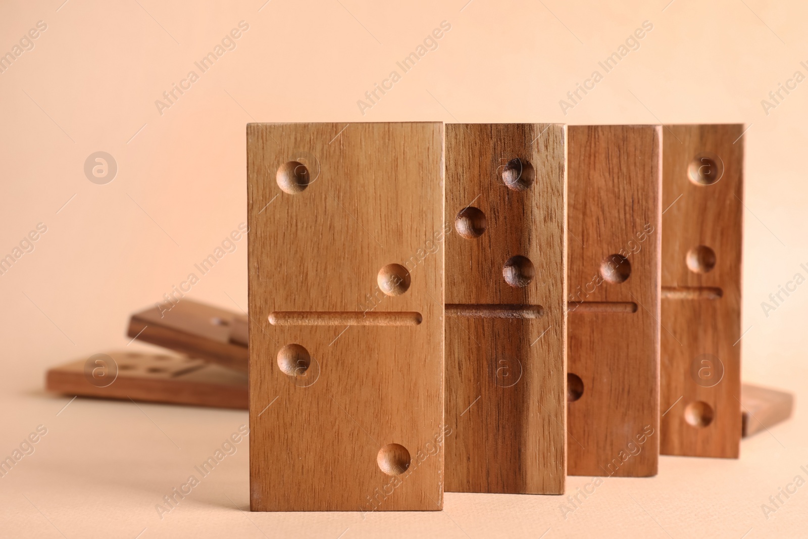 Photo of Wooden domino tiles with pips on beige background