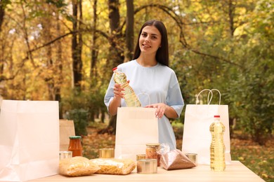 Portrait of volunteer packing food products at table in park