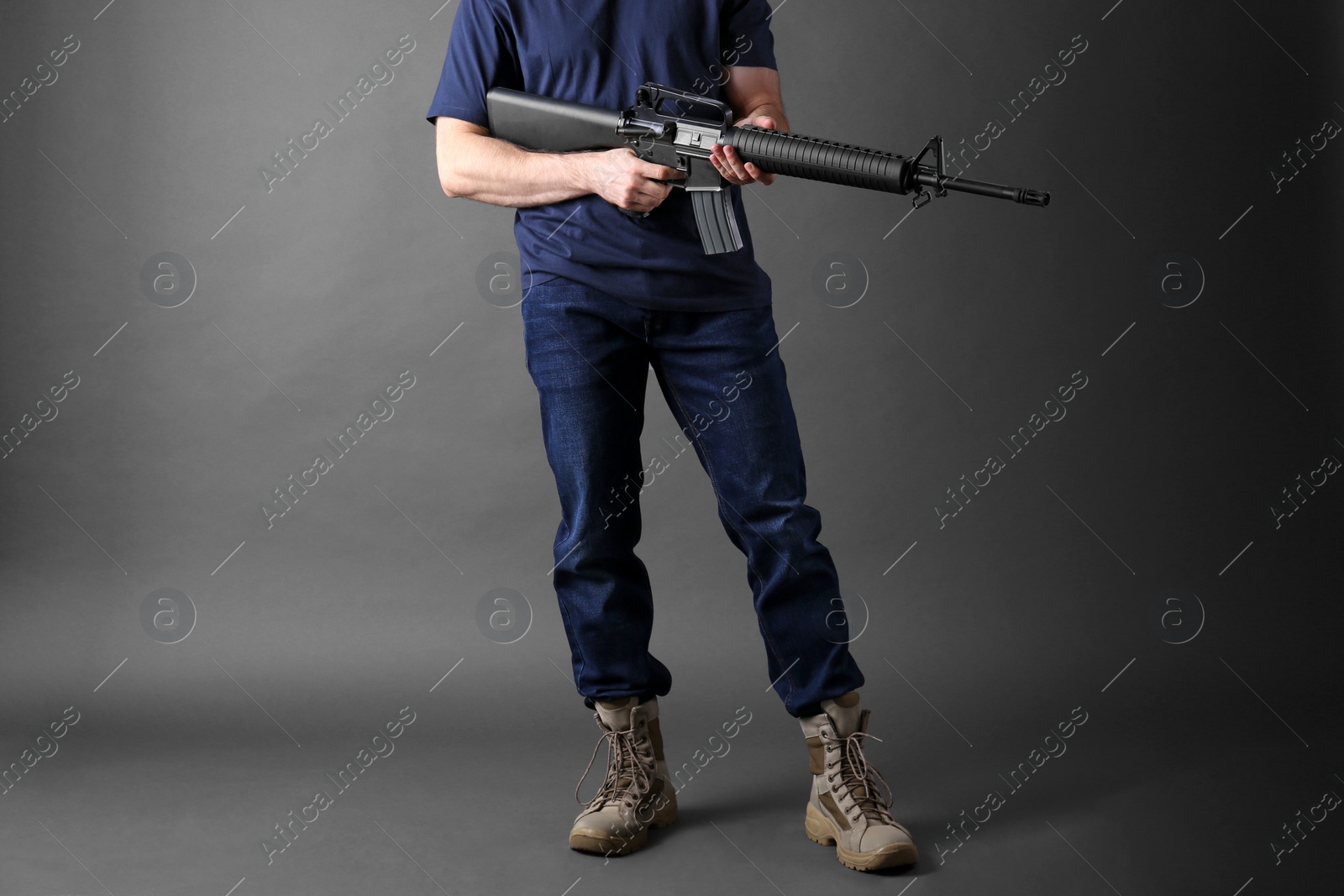 Photo of Assault gun. Man holding rifle on dark background, closeup