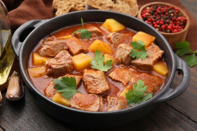 Photo of Delicious goulash in pot on wooden table, closeup