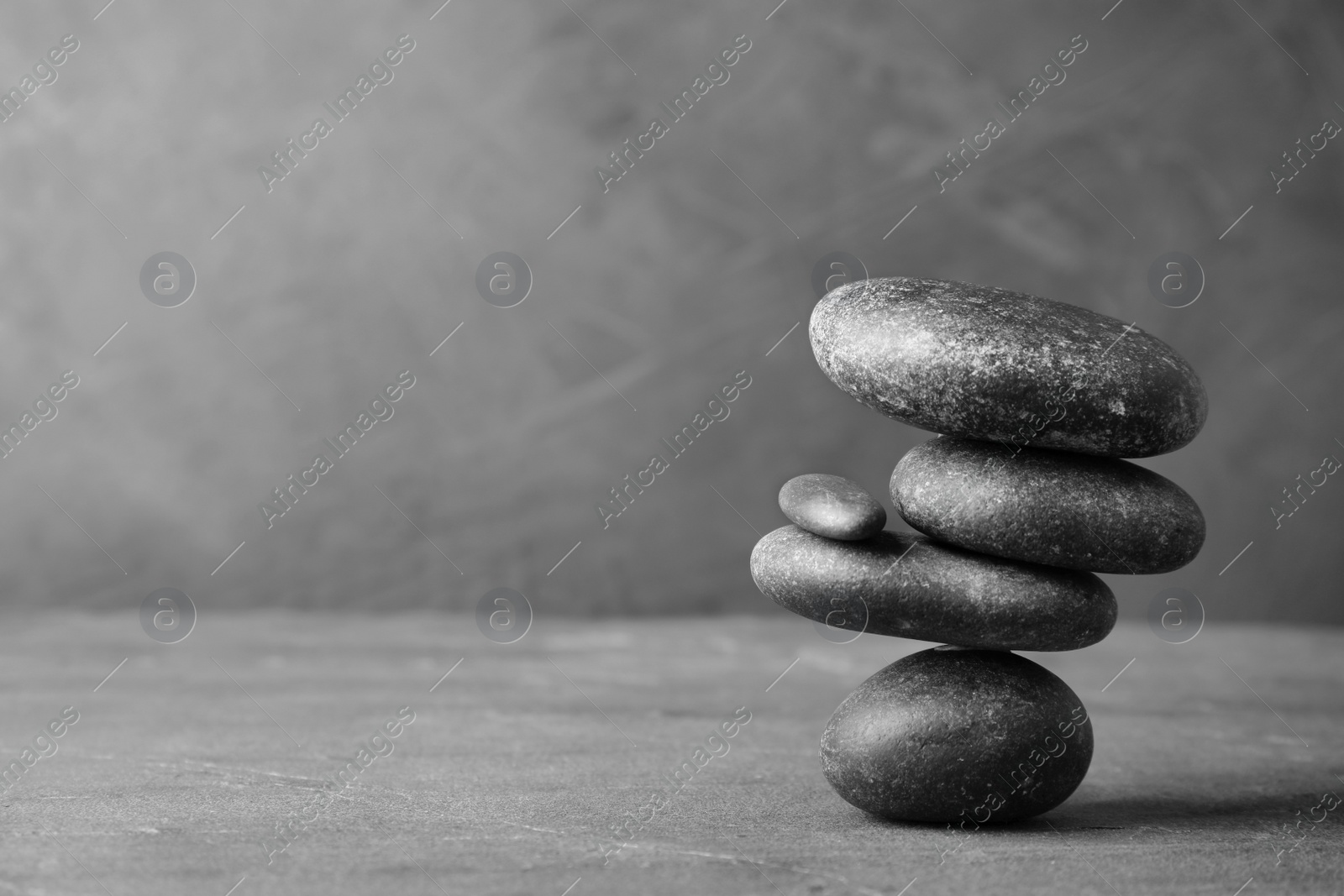 Photo of Stack of zen stones on table against grey background. Space for text