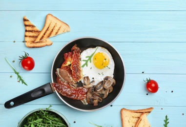 Photo of Pan with fried egg, bacon and vegetables on table