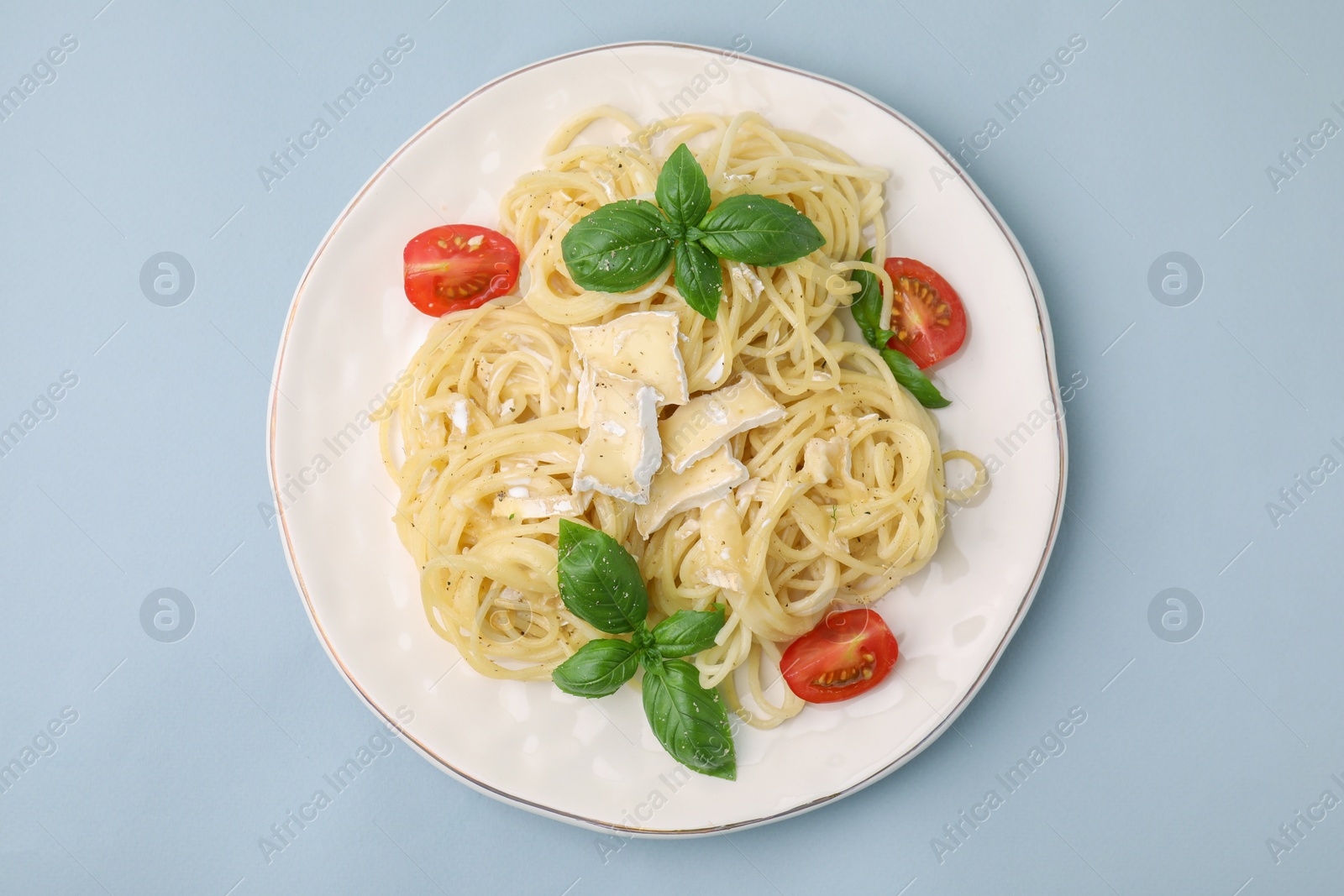 Photo of Delicious pasta with brie cheese, tomatoes and basil leaves on grey background, top view