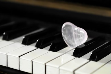 Photo of Beautiful heart shaped stone on piano keys, closeup. Space for text