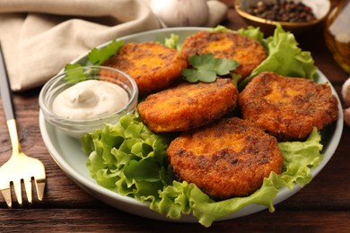 Tasty vegan cutlets served with sauce on wooden table, closeup