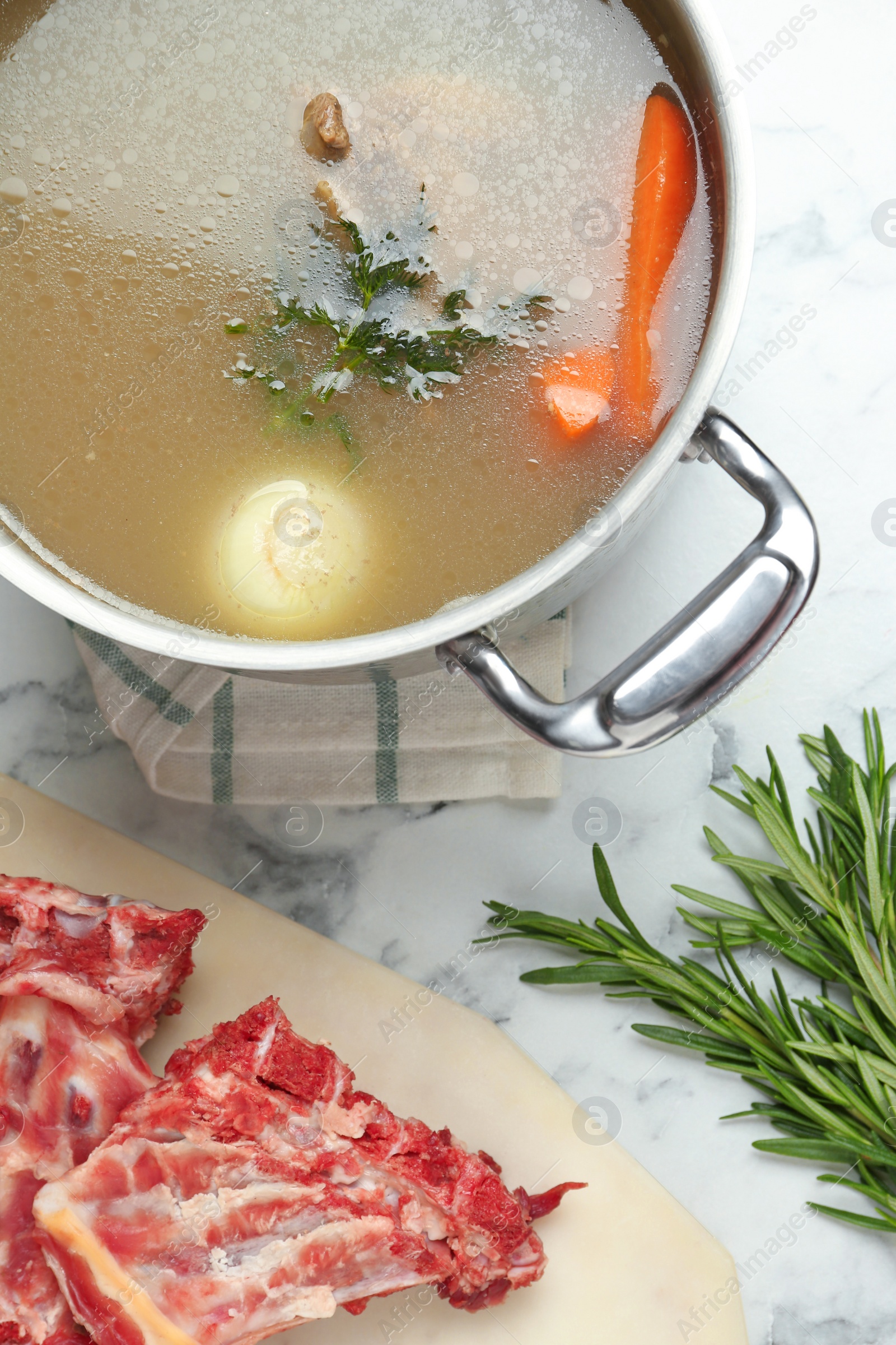 Photo of Delicious homemade bone broth and ingredients on white marble table, flat lay