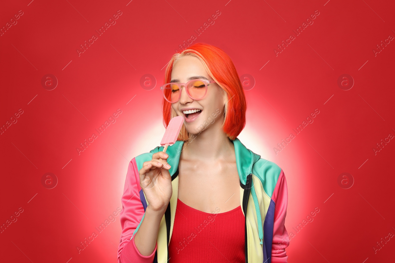 Photo of Beautiful young woman with bright dyed hair eating ice cream on color background