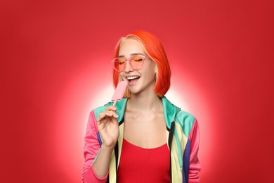 Photo of Beautiful young woman with bright dyed hair eating ice cream on color background