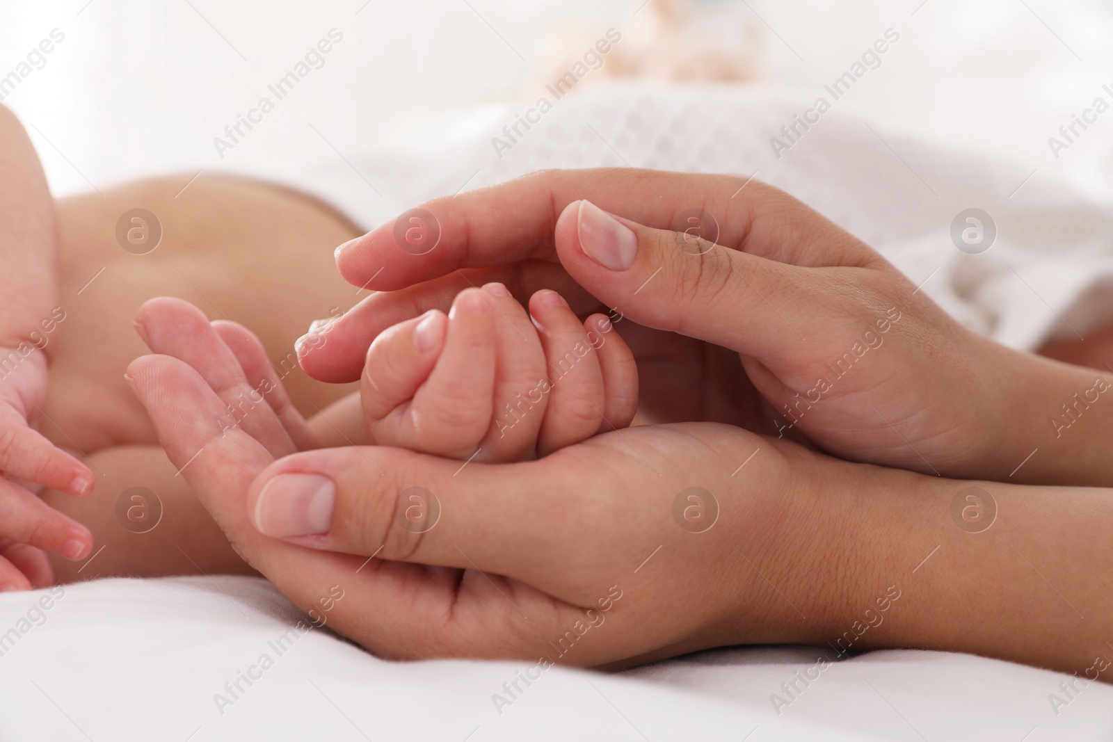 Photo of Mother with her cute baby on bed at home, closeup of hands