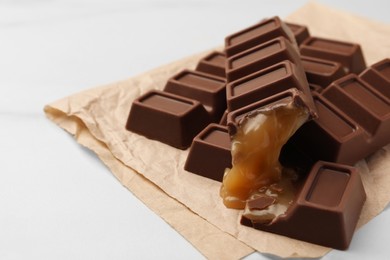 Tasty chocolate bars with caramel on white table, closeup. Space for text