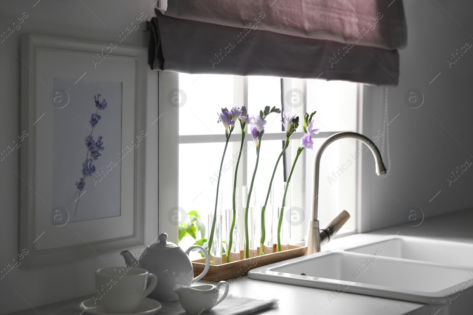 Photo of Beautiful freesia flowers near window in kitchen