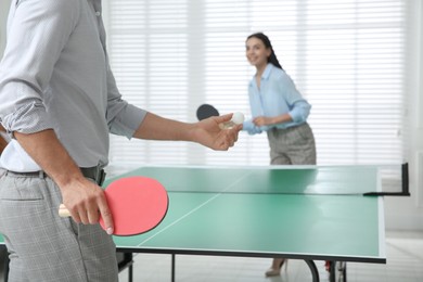Photo of Business people playing ping pong in office, focus on tennis racket