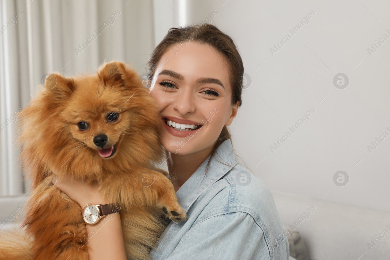 Photo of Happy young woman with cute dog at home