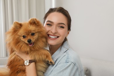 Happy young woman with cute dog at home