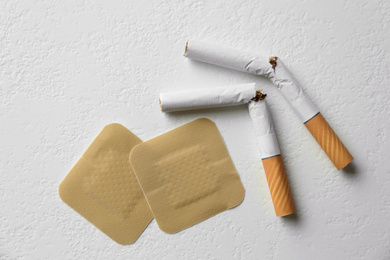Photo of Nicotine patches and broken cigarettes on white background, flat lay