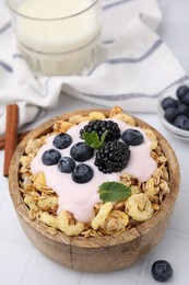 Tasty granola, yogurt and fresh berries in bowl on white tiled table. Healthy breakfast