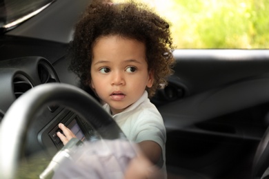 Photo of Little African-American girl alone inside car, space for text. Child in danger