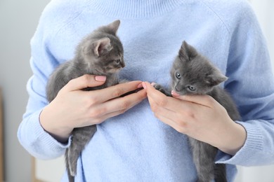 Photo of Woman with cute fluffy kittens indoors, closeup