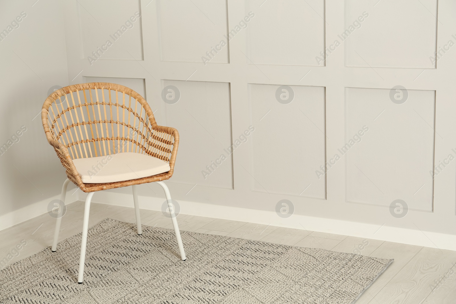 Photo of Stylish wicker armchair near light wall in room. Space for text