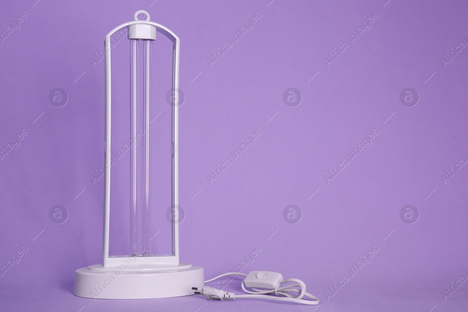Photo of Ultraviolet lamp on violet background, space for text