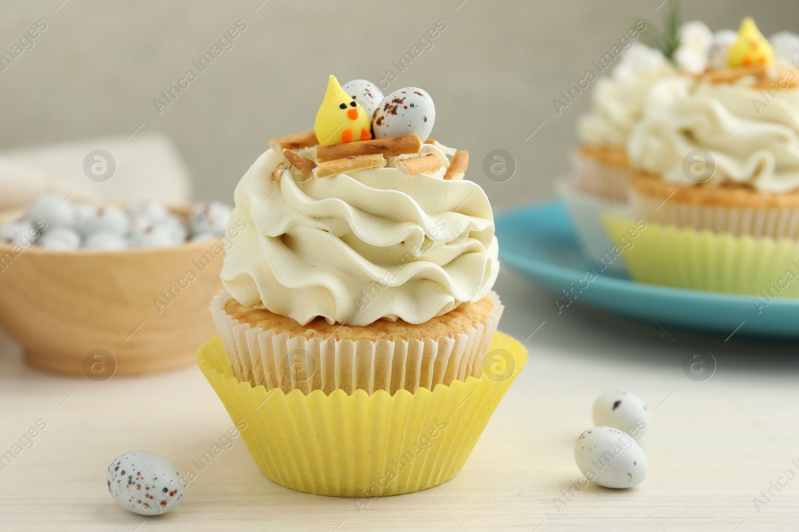 Photo of Tasty Easter cupcakes with vanilla cream on light wooden table