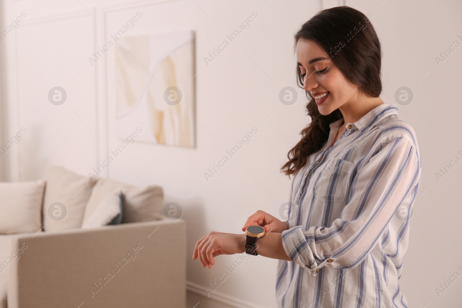 Photo of Young woman using smart watch at home, space for text