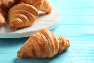 Photo of Fresh croissants on light blue wooden table. French pastry