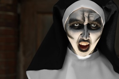 Portrait of scary devilish nun on blurred background, space for text. Halloween party look