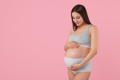 Photo of Beautiful pregnant woman in comfortable maternity underwear on pink background, space for text