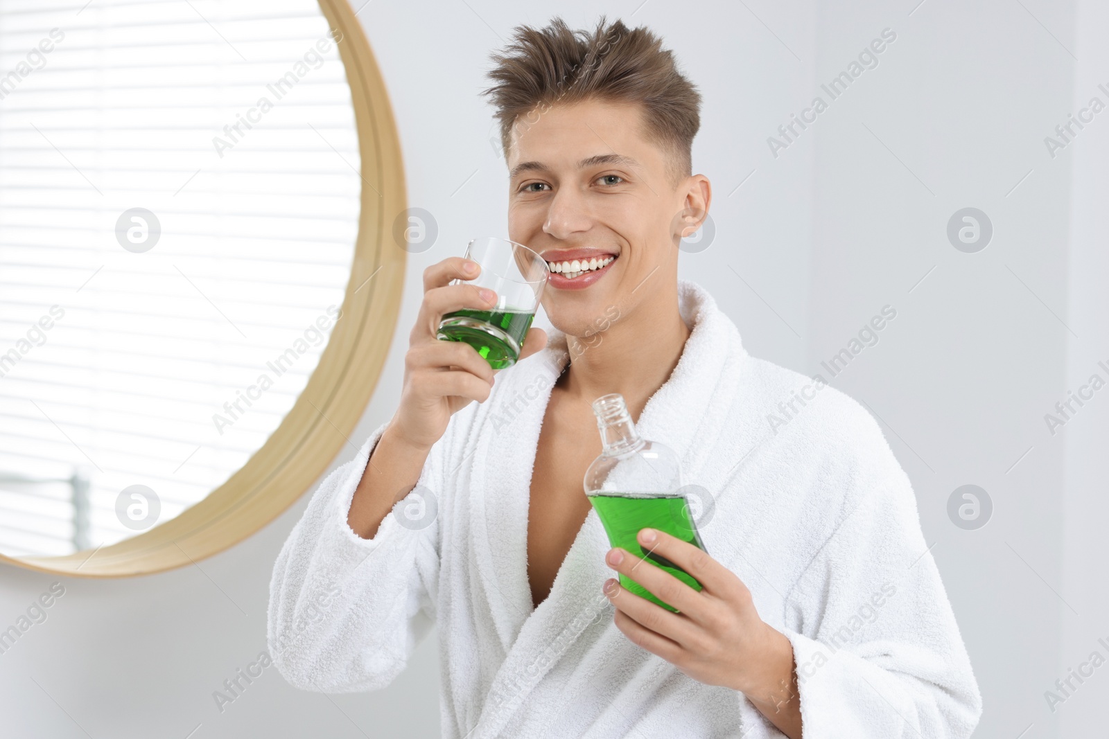 Photo of Young man using mouthwash in bathroom. Oral hygiene