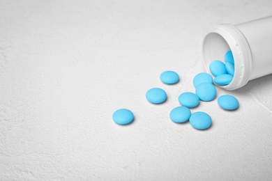 Photo of Container with blue pills on white background