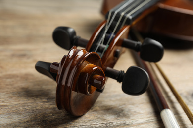 Photo of Beautiful violin and bow on wooden table, closeup