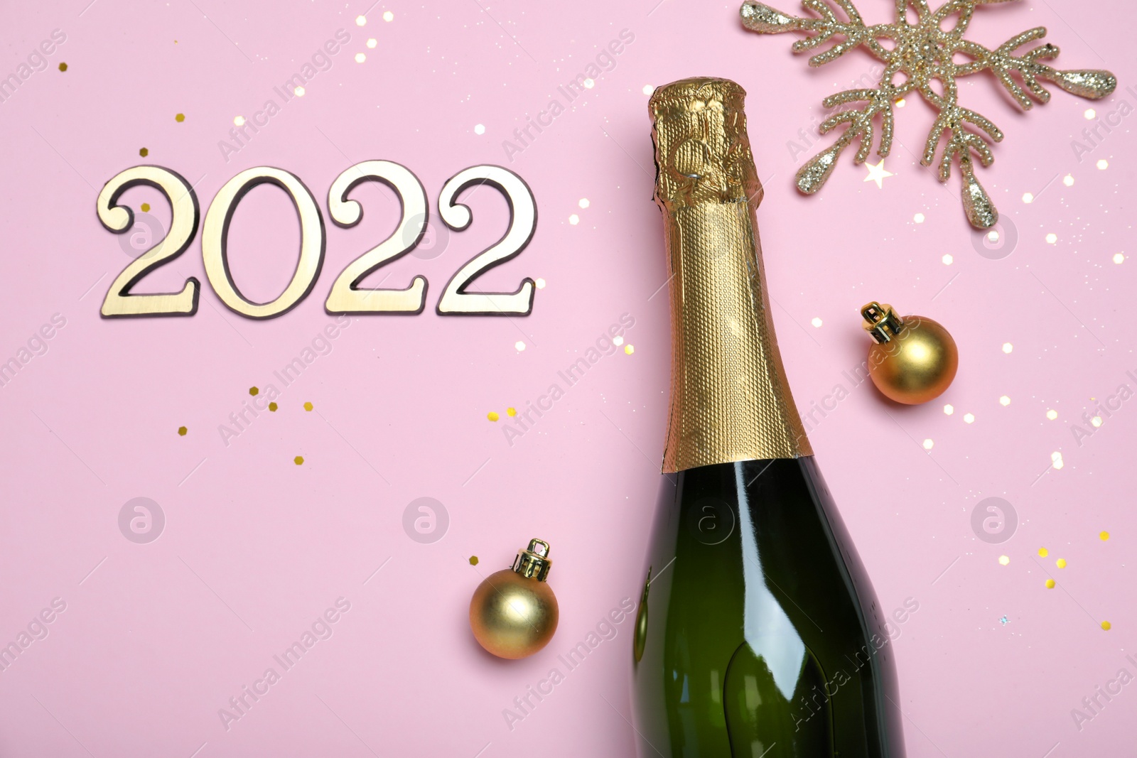 Photo of Happy New Year 2022! Flat lay composition with bottle of sparkling wine on pink background, space for text