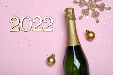 Photo of Happy New Year 2022! Flat lay composition with bottle of sparkling wine on pink background, space for text