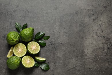 Photo of Fresh ripe bergamot fruits with green leaves on grey table, flat lay. Space for text