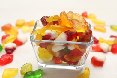 Photo of Many different delicious gummy candies on white wooden table, closeup