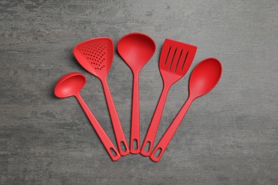 Photo of Set of red cooking utensils on grey table, flat lay